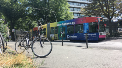 Fahrrad im Vordergrund und eine vorbeifahrende Straßenbahn im Hintergrund